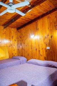 查斯科穆斯多纳玛格丽塔山林小屋的木墙内的房间,配有两张紫色的床