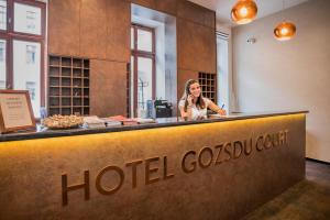 布达佩斯Hotel Gozsdu Court的一名妇女在酒店开销柜台后面的手机上讲话