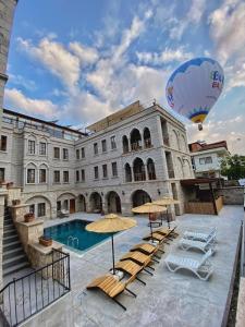 格雷梅卡帕多西亚大酒店的一座带游泳池和热气球的大型建筑