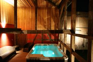 BolsenheimLes Authentics - Le Domaine d'Autrefois & Spa的木墙客房的按摩浴缸