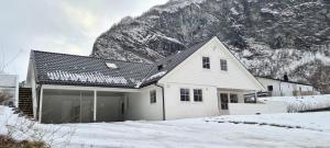 艾于兰Cheerful 4-bedroom home with fireplace, 1,5km from Flåm center的雪中白房子,山中