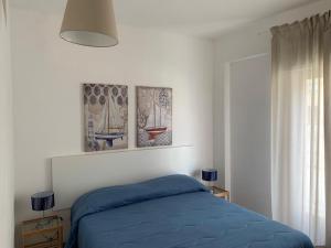 夏卡Appartamento Mare Blu的卧室配有一张蓝色的床,墙上挂有三张照片