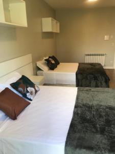 圣弗朗西斯科-迪保拉Piavi Residencial的配有白色床单的酒店客房内的两张床