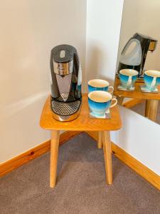 波特里An-Airidh Bed & Breakfast Portree的一张带两个杯子的木桌旁咖啡壶