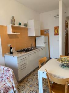 夏卡Appartamento Mare Blu的厨房配有白色橱柜、桌子和桌子以及用餐室。