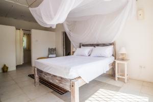 迪亚尼海滩Flamboyant Diani Beach的一间卧室配有一张带天蓬的床