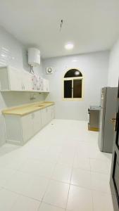 欧拉همس العلا للشقق المفروشة的厨房配有白色橱柜和白色瓷砖地板。