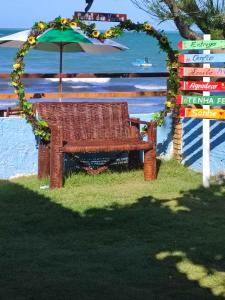 伊卡普伊Restaurante & Pousada Portal dos Ventos的海滩上一把伞下的柳条长凳