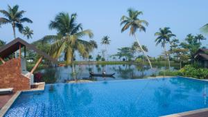 库玛拉孔Gokulam Grand Resort & Spa, Kumarakom的棕榈树度假村前的游泳池