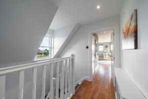 布罗迪菲利Thatched Cottage的房屋内的楼梯,拥有白色的墙壁和木地板