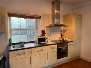泰恩河畔纽卡斯尔Wall St flat by HNFC Stays - Netflix & Popcorn的厨房配有微波炉和水槽。