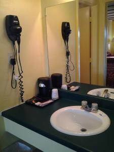 雨果Holiday Motel的一间带水槽的浴室和墙上的两部电话
