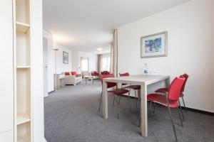 苏黎世EMA House Serviced Apartments Aussersihl的一间带桌子和红色椅子的用餐室