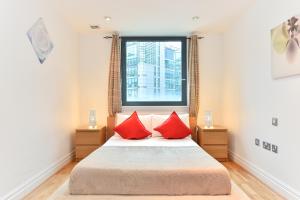 伦敦Paddington Gardens的一间卧室配有一张带红色枕头的床和一扇窗户