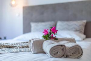 ArrifesCarvão Pdl Inn的一间卧室配有毛巾,床上有一朵鲜花