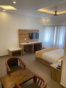 蒙纳Munnar Ice Queen Resorts的酒店客房设有一张床和一张带电视的书桌。