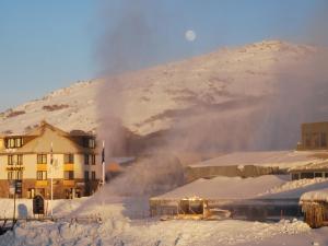 佩里舍峡谷瑞雪庄园酒店的一座雪地中的建筑,背景是一座山
