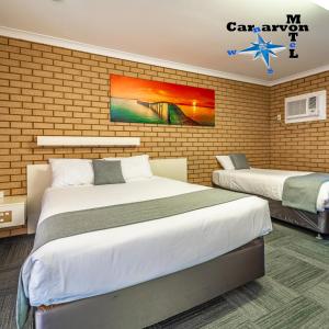 卡那封Carnarvon Motel的一间卧室设有两张床和砖墙