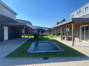 坎珀兰luxe Villa Maroma Mistral aan Veerse meer met 4 Ebikes GasBBQ & EV laadpaal的一座建筑中间带游泳池的庭院
