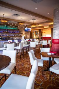 卡尔加里Hotel 11, MOD A Sonesta Collection的一间设有白色桌椅的餐厅和一间酒吧