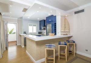 EsteponaHB Comfortable Beachfront Holiday Apartment的厨房配有蓝色橱柜和带凳子的台面