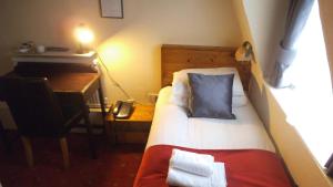 伦敦阿兰大楼酒店的小房间设有一张床、一张桌子和一张书桌