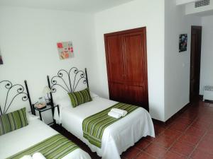 Villanueva del FresnoCasa Rural La Aduana的白色墙壁客房的两张床