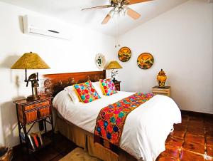 卡波圣卢卡斯Collection O Casa Bella Hotel Boutique, Cabo San Lucas的一间卧室配有一张带色彩缤纷枕头的床和吊扇。
