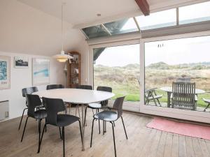 罗胡斯6 person holiday home in Pandrup的一间带桌椅和大窗户的用餐室
