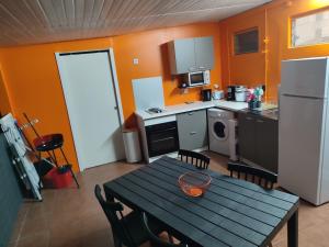 勒马兰Appartement Kelysa的一间带桌子的厨房和一间带橙色墙壁的厨房