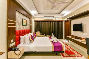 西里古里Mount Amara Hotel & Spa, Siliguri的一间酒店客房,配有一张床和一台电视