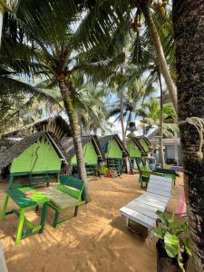 高尔Oynise Beach Cabin的一片拥有绿色野餐桌和棕榈树的海滩