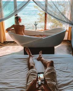 蓬圭The Island - Pongwe Lodge的躺在床上的男人,在浴缸里拍一张女人的照片