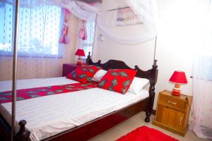 蒙巴萨Lux Suites Royal Family Apartment Nyali的一间卧室配有一张带红色枕头的天蓬床
