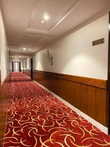 泰布克Biz Hotel Apartments的一条空的走廊,上面有红金色的地毯