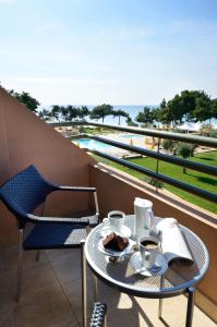 波托什皇家天堂海滩度假酒店及水疗中心的阳台上的桌子上放着两杯咖啡和蛋糕