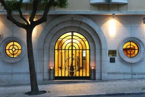 里斯本Hotel Britania Art Deco - Lisbon Heritage Collection - Avenida的前面有树门的建筑
