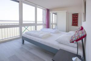 布雷斯肯斯Kustverhuur, Appartement aan zee, Port Scaldis 05042的一间卧室设有两张床和大窗户