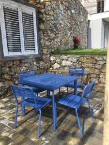 菲纳莱利古雷Belvedere20guesthouse的蓝色的桌子和椅子,带有石墙