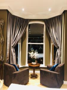道格拉斯Halvard Hotel的客厅配有两把椅子、一张桌子和一扇窗户