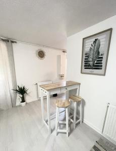 圣艾蒂安Le Golf Balnéo - Cosy & SPA - Appartement的白色的厨房配有一张桌子和两张凳子