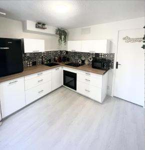 圣艾蒂安Le Golf Balnéo - Cosy & SPA - Appartement的厨房配有白色橱柜和黑色用具