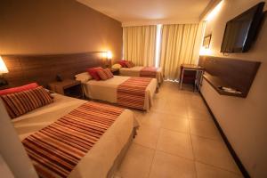 维拉卡洛斯帕兹Hotel Estilo MB - Villa Carlos Paz的酒店客房设有两张床和一台平面电视。