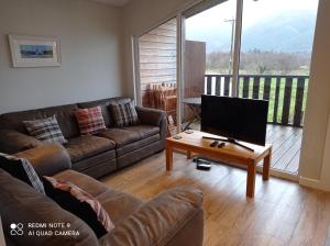 格伦科Glencoe view lodge的客厅配有沙发和带电视的桌子