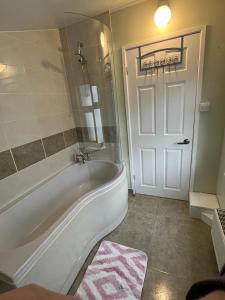 布里斯托Cosy Entire residential home. Staple Hill. Bristol的一间带白色浴缸的浴室和一扇地毯的门
