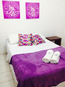 拉巴拉德纳圣米格尔Pousada Villa Joia的一间卧室配有一张带紫色床单和2条毛巾的床