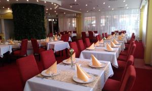 里马夫斯卡索博塔金牛酒店的用餐室配有白色的桌子和红色的椅子