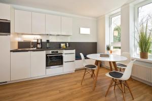 黑灵斯多夫Strand-Park Strand-Park 204的厨房配有白色橱柜和桌椅