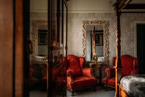 莱瑟姆-圣安妮The Queens Hotel的一间卧室配有红色的椅子、一张床和镜子