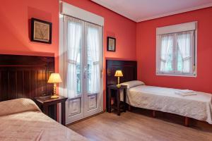 坎加斯-德奥尼斯Hotel y Apartamentos La Lonja的红色卧室设有两张床和两个窗户